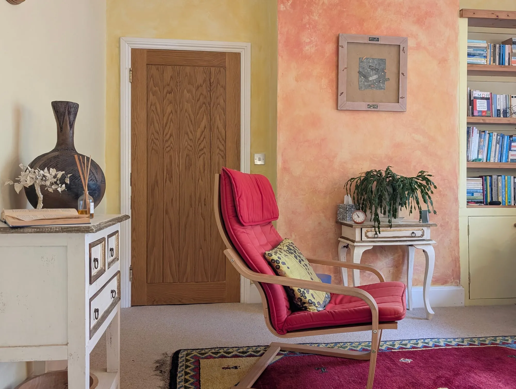 The consulting room in Henleaze, with a red armchair and warm plaster walls